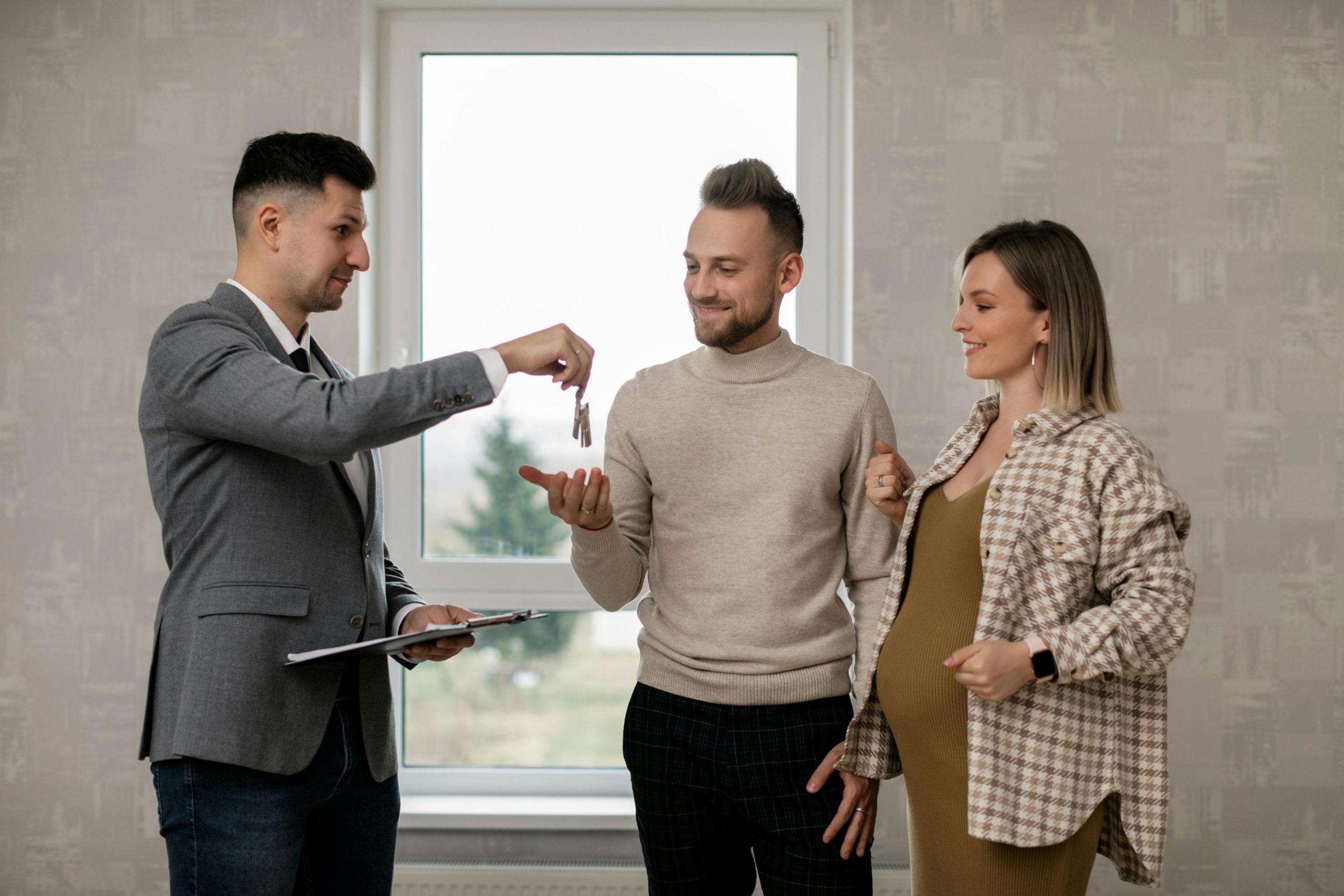 A real estate agent handing keys to a couple, symbolizing successful collaboration for new real estate agents launching their careers.